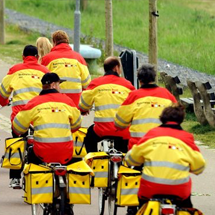 Foto van fietsende bezorgers van Business Post in geel-oranje kleding, tevens link naar pagina Business Post.